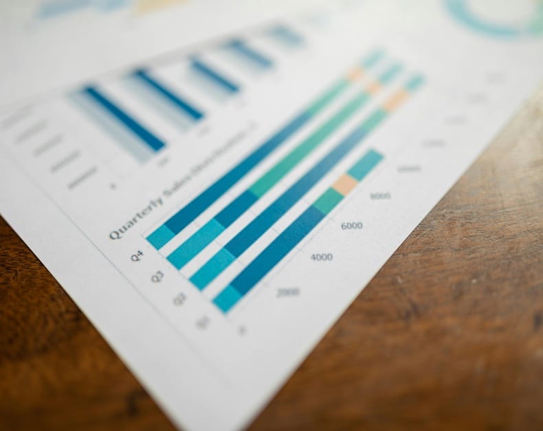 Close-up of a multicolored bar chart on a white sheet resting on a wooden table.