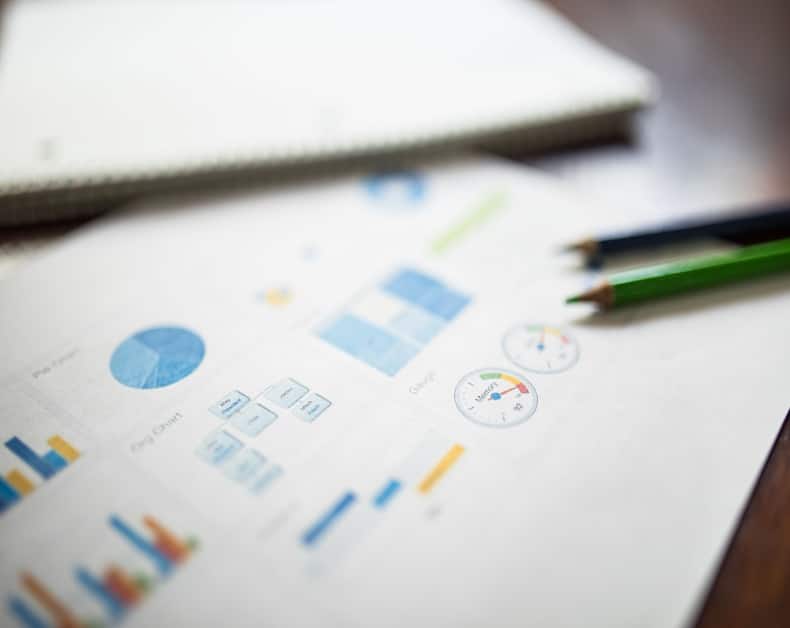 Business report page with blue charts and gauge indicators on a desk, pencils nearby